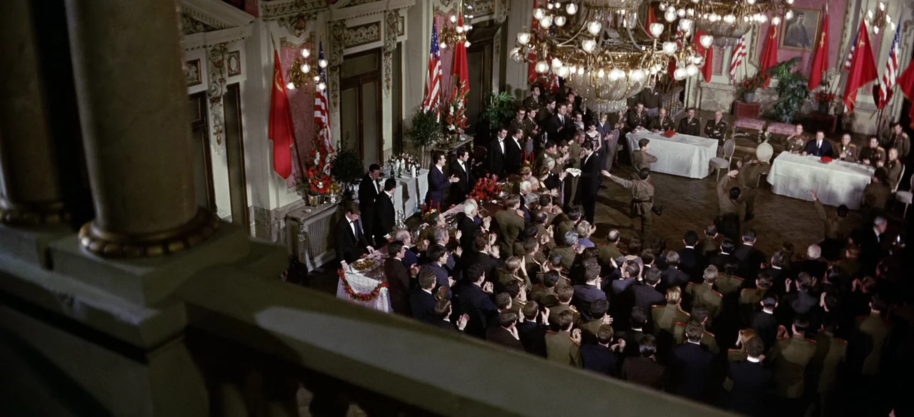 Patton (1970) movie still: wide — A grand, ornate ballroom features high ceilings, chandeliers, and numerous American and Soviet flags. A large…