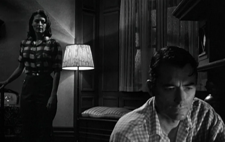 On The Beach (1959) movie still: medium — A dimly lit residential space at night features paneled walls and a window with curtains. A man in the…