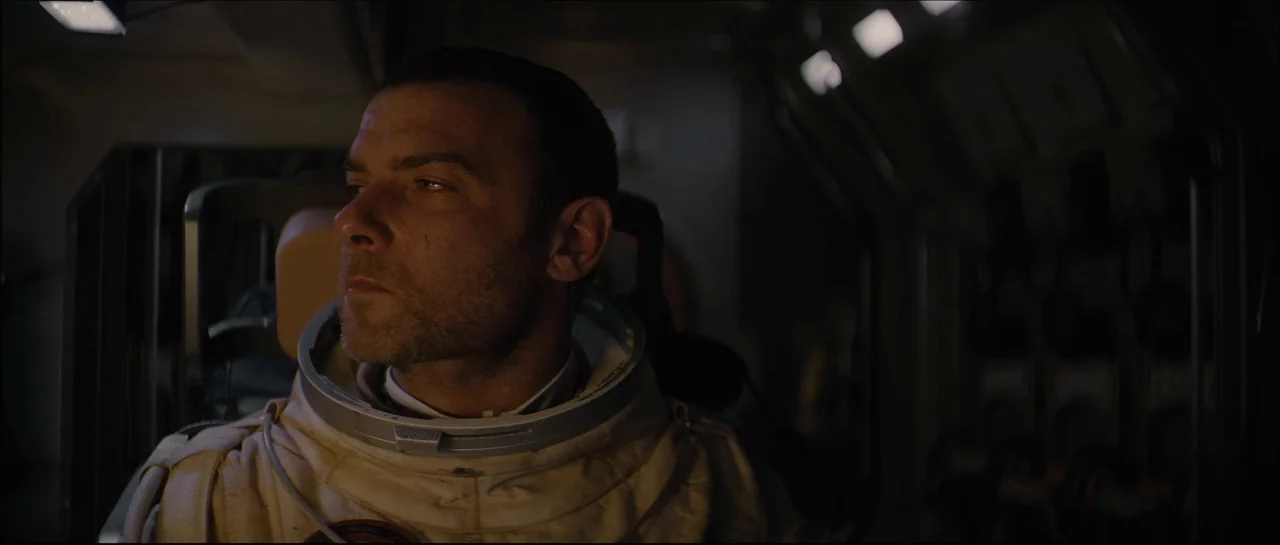 The Last Days On Mars (2013) movie still: medium — The interior of a dimly lit, industrial-style spacecraft cockpit with metallic wall panels. A man…