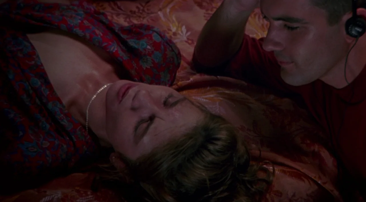 Tie Me Up! Tie Me Down! (1989) movie still: medium — A dimly lit room with ornate, patterned fabric covers on the bed surface. A man wearing…