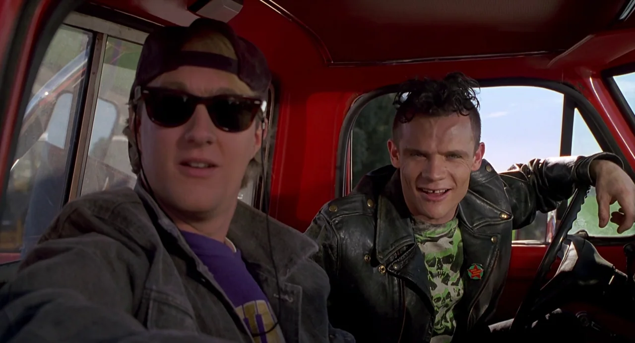 Back To The Future Part III (1990) movie still: medium — The interior of a red truck cab features two men sitting side by side. One man wears…