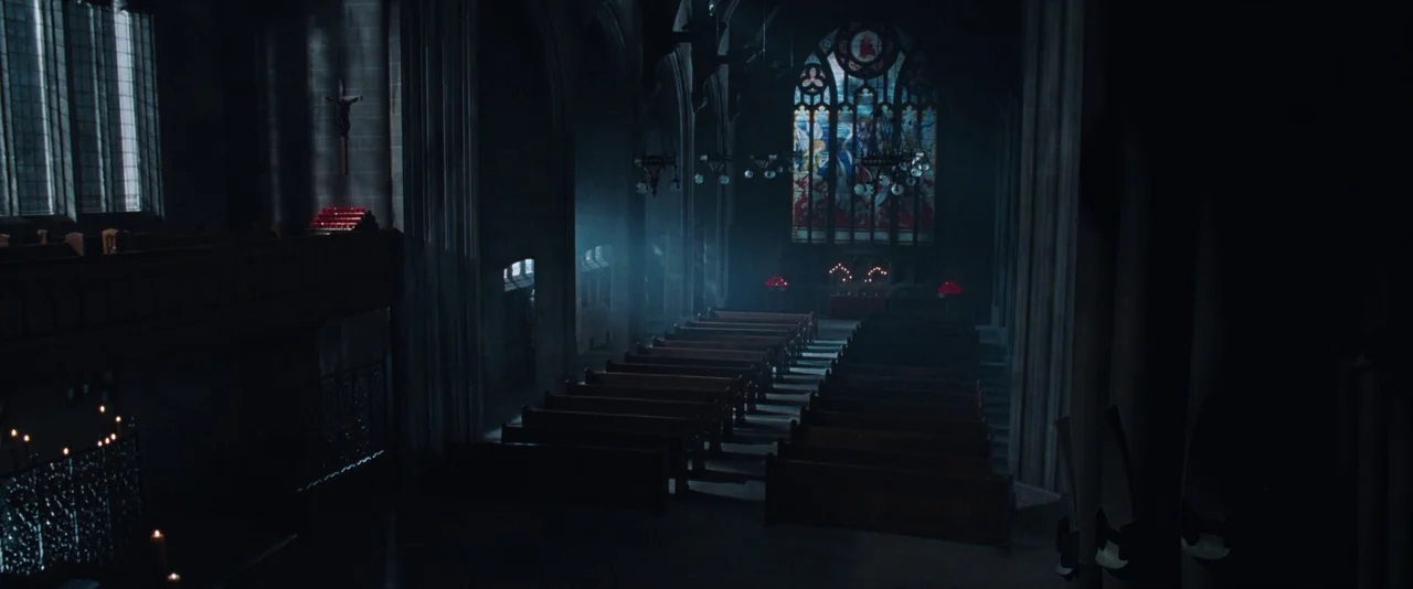 Resident Evil: Apocalypse (2004) movie still: establishing — A dark stone cathedral interior featuring rows of empty wooden pews and arched…