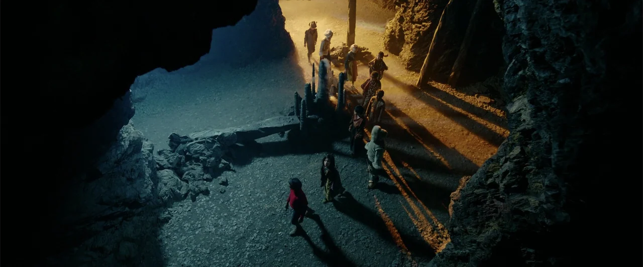 Jim Button and Luke the Engine Driver (2018) movie still: wide — A dark rocky cave features a group of children walking along a gravel floor.…
