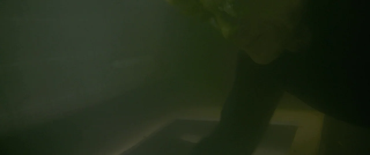 All Is Lost (2013) movie still: closeup — A dark subterranean space is filled with thick, low-hanging olive green smoke. An elderly man in glasses…