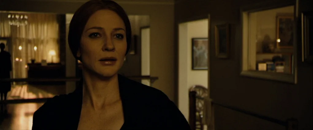 The Curious Case Of Benjamin Button (2008) movie still: medium — A dimly lit indoor residential corridor with warm light spill from an adjacent…
