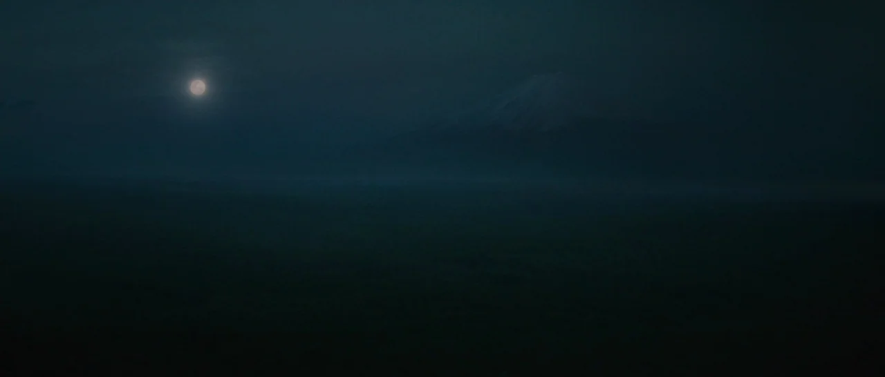 The Sea of Trees (2015) movie still: establishing — A dark, misty landscape features the silhouette of a mountain under a full moon. The scene is…