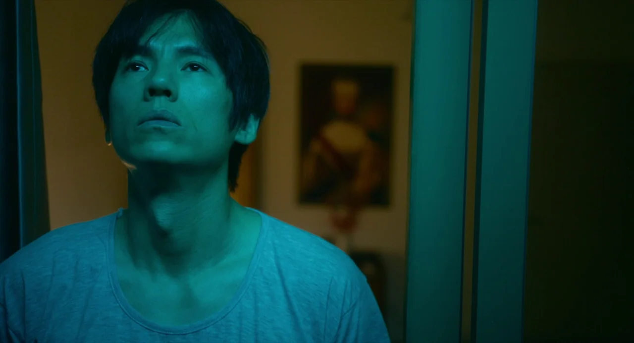 White River (2023) movie still: medium — A modern interior space is visible behind a man standing in a doorway. A framed painting hangs on the wall…