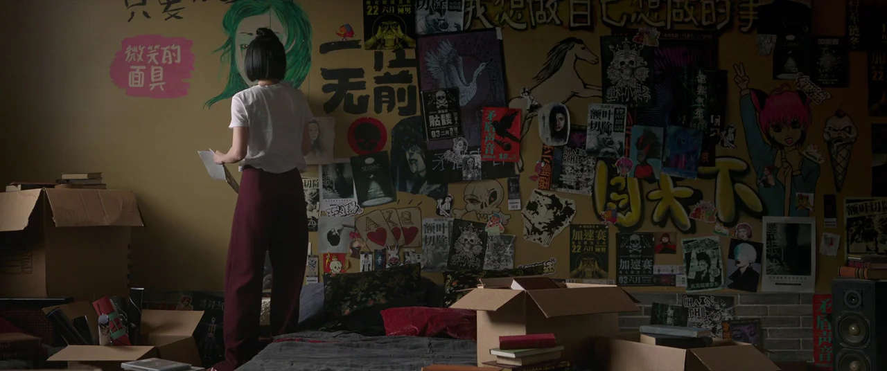 Shang-Chi and the Legend of the Ten Rings (2021) movie still: medium — A wall is plastered with various colorful posters, stickers, and hand-drawn…