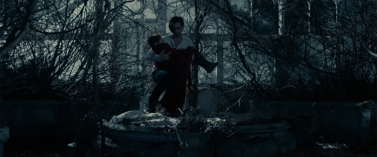 Winter's Tale (2014) movie still: medium — A glass-walled conservatory is overgrown with thick, leafless tangled branches and dry thickets. A man…