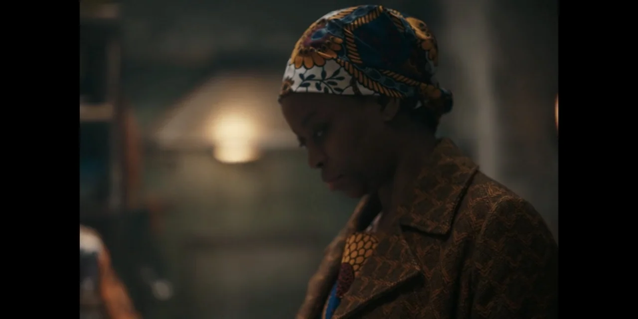 Autumn Beat (2022) movie still: medium — A dimly lit indoor space featuring textured wall surfaces and a warm background light. A woman wearing a…
