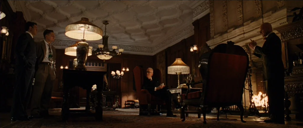 Shutter Island (2010) movie still: wide — A spacious, dimly lit wood-paneled study features ornate ceiling moldings and a large fireplace. Four men…