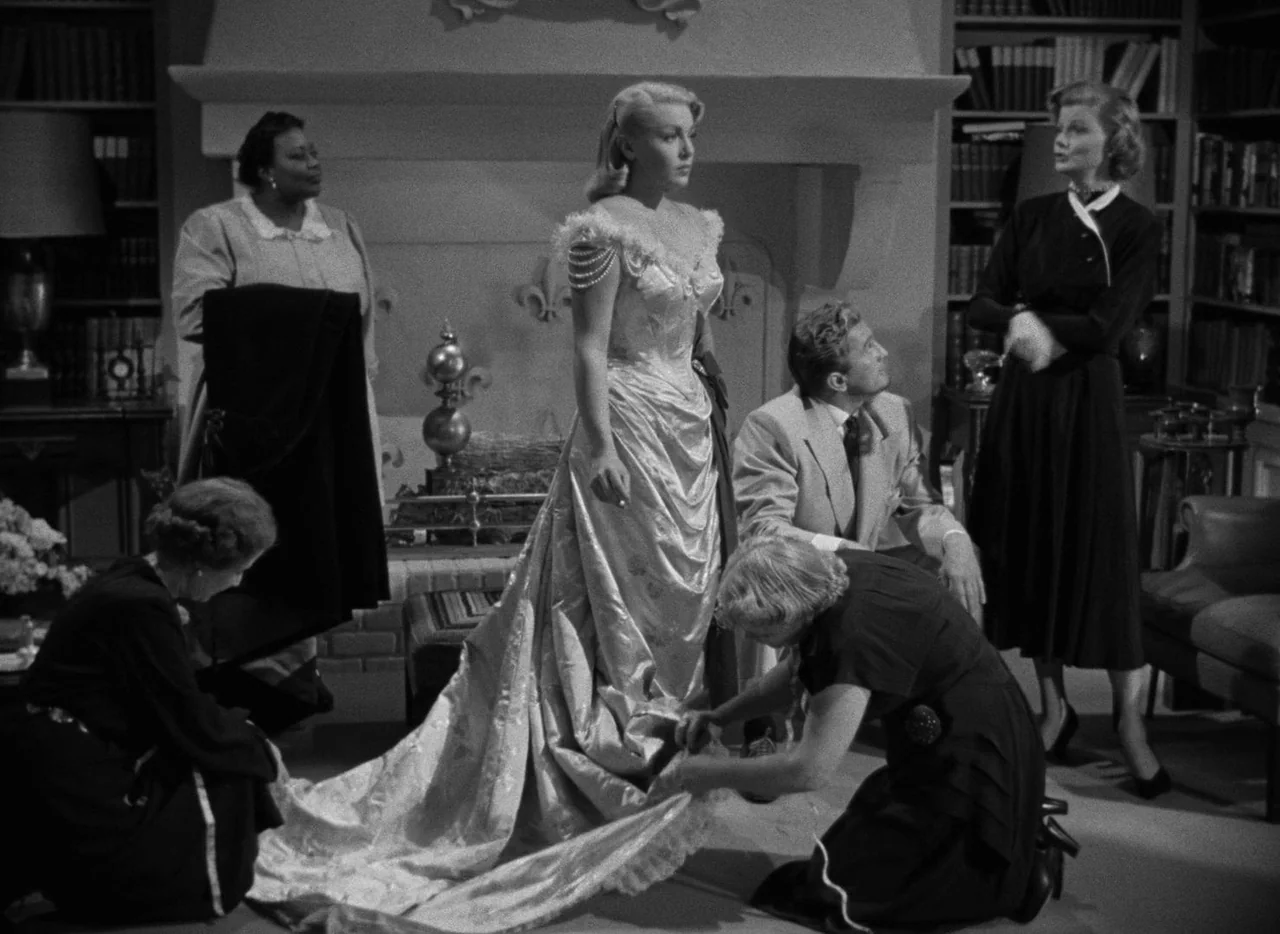The Bad and the Beautiful (1952) movie still: fullbody — A spacious room features floor-to-ceiling bookshelves and a large stone fireplace mantle.…