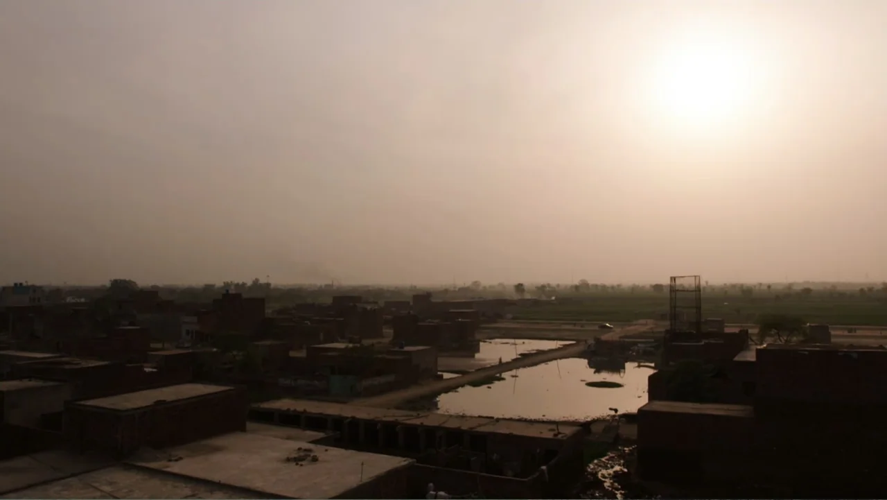 A Girl in the River: The Price of Forgiveness (2015) movie still: establishing — A hazy rural village landscape with scattered brick dwellings and a…
