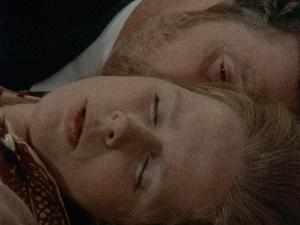 Scenes from a Marriage (1973) movie still: closeup — Two individuals lie close together in a dimly lit, soft-focused interior setting. Their faces…