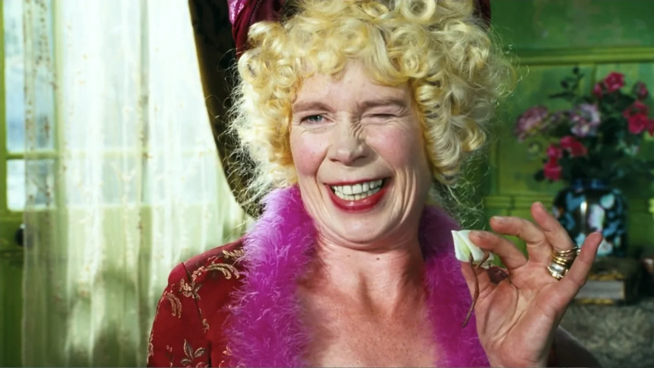 Nanny McPhee and the Big Bang (2010) movie still: closeup — A room with vibrant green walls features a bouquet of flowers in the background. A woman…