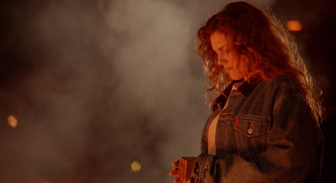Hellraiser (1987) movie still: medium — A woman stands in the dark outdoors surrounded by thick, billowing orange-tinted smoke. She looks down at a…