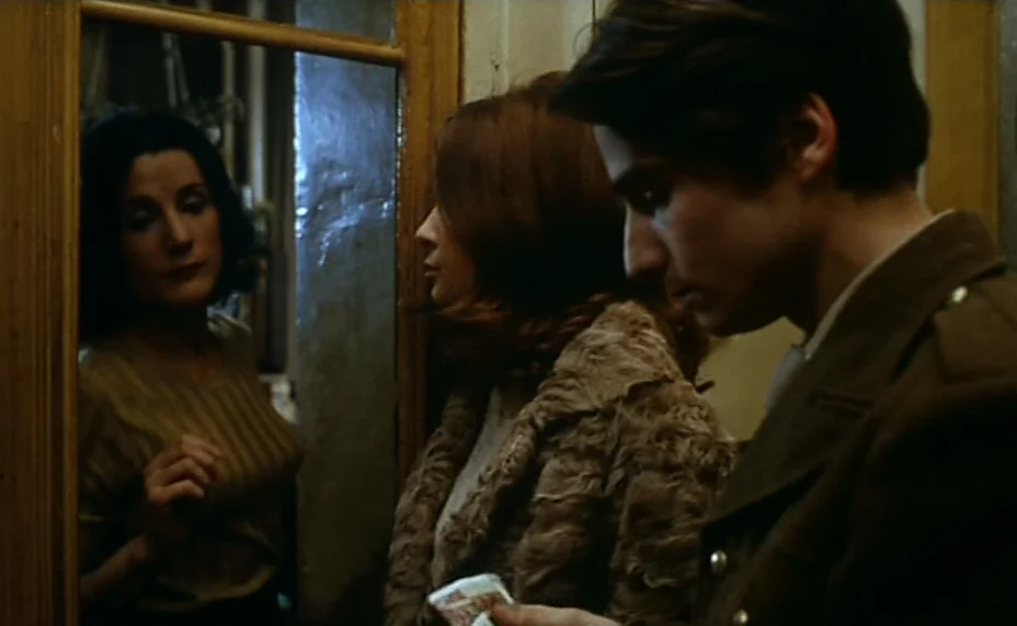 Stolen Kisses (1968) movie still: medium — A narrow interior hallway with wooden trim and a large vertical wall mirror. A man in a dark jacket…