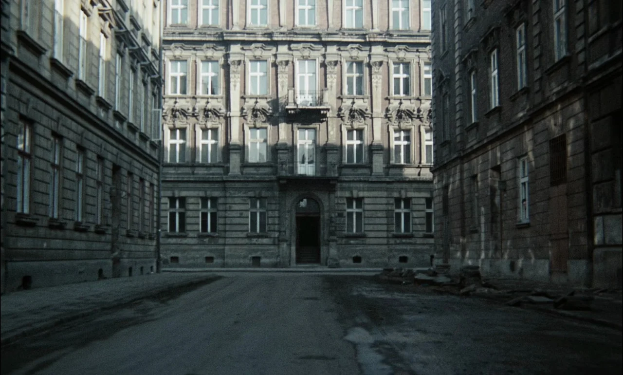 The Third Part of the Night (1971) movie still: establishing — A symmetrical view of a tall, stone apartment building facade at the end of street.…
