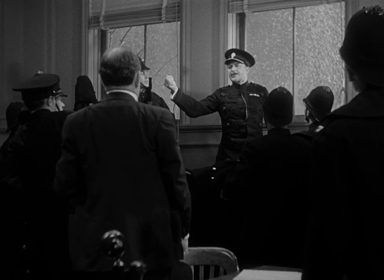 The Invisible Man (1933) (1933) movie still: medium — A group of uniformed police officers stands in a dimly lit, wood-paneled room. An officer at…