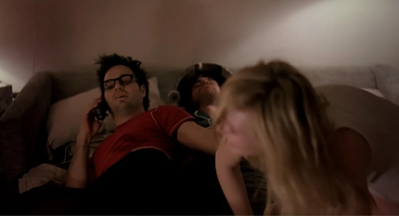 Eternal Sunshine of the Spotless Mind (2004) movie still: medium — A dimly lit room features a bed with grey bedding and neutral walls. A man in a…