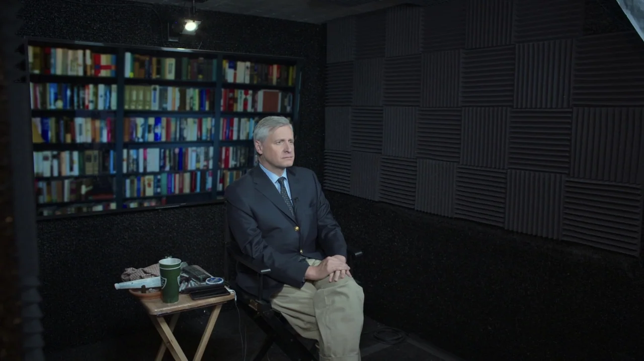 The Soul of America (2020) movie still: medium — A recording studio features dark acoustic foam walls and a large shelf of books. A man in business…