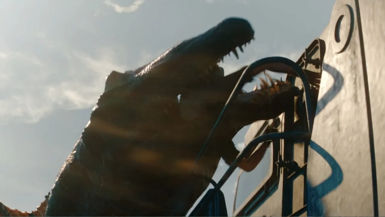 Jurassic World Rebirth (2025) movie still: medium — A massive creature with sharp teeth claws at the side of a metal train car. The beast grips the…