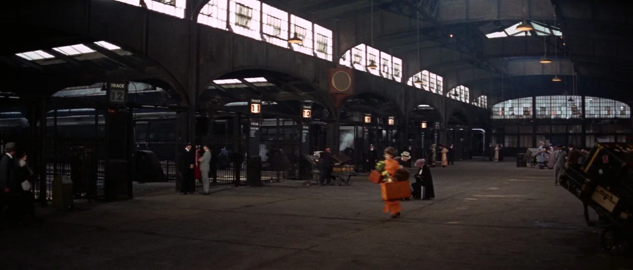 Funny Girl (1968) movie still: wide — A sprawling, high-ceilinged train depot features heavy steel arches and multiple numbered tracks. Various…