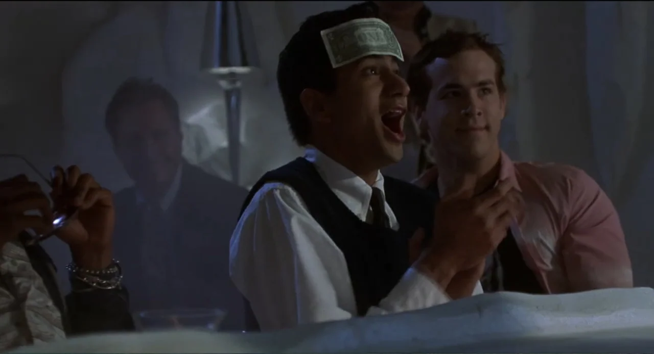 National Lampoon's Van Wilder (2002) movie still: medium — A dark, dimly lit bar interior features three men seated together at a table. A man in…