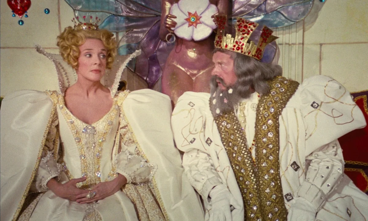 Donkey Skin (1970) movie still: medium — A lavish fantasy throne room features ornate white garments and a large decorative backdrop. The king and…