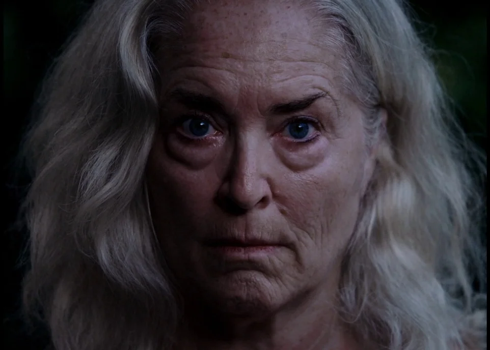 Krisha (2015) movie still: closeup — A close-up shot focuses on an elderly woman set against a dark outdoor background. She stares directly into the…