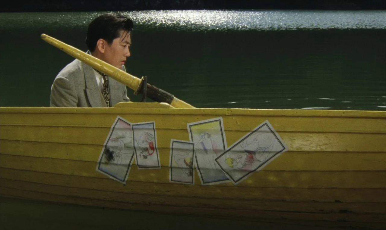 Yumeji (1991) movie still: medium — A man sits in a wooden rowboat on a dark, calm body of water. Several small illustrated drawings are taped to…