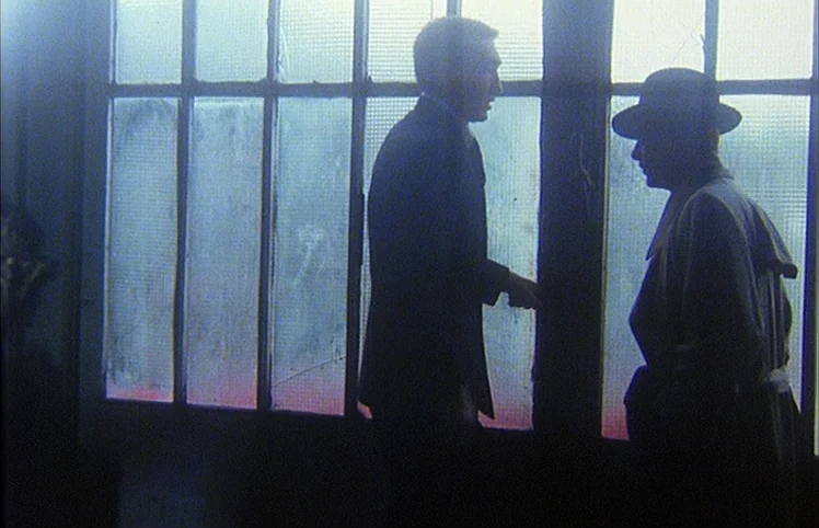 Lili Marleen (1981) movie still: medium — Two men stand before a large multi-pane glass window with translucent textured panes. The pair remains in…