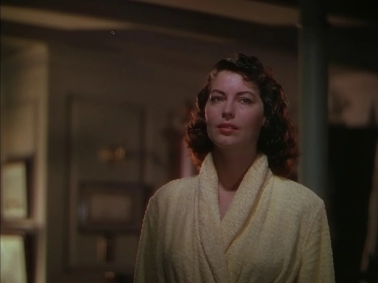 Pandora and the Flying Dutchman (1951) movie still: medium — A dimly lit room with out-of-focus background furniture and a column. A woman in a…