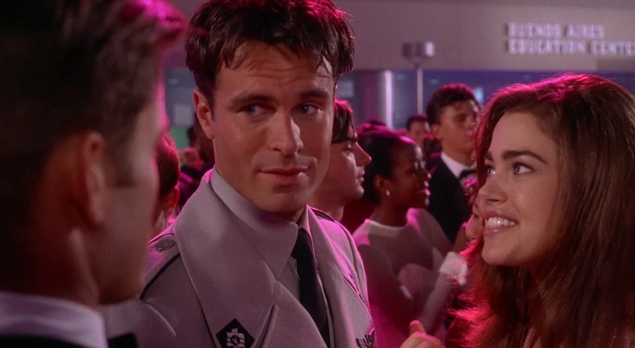 Starship Troopers (1997) movie still: medium — A high school gym decorated for a formal dance features students in formal attire. A man in a uniform…