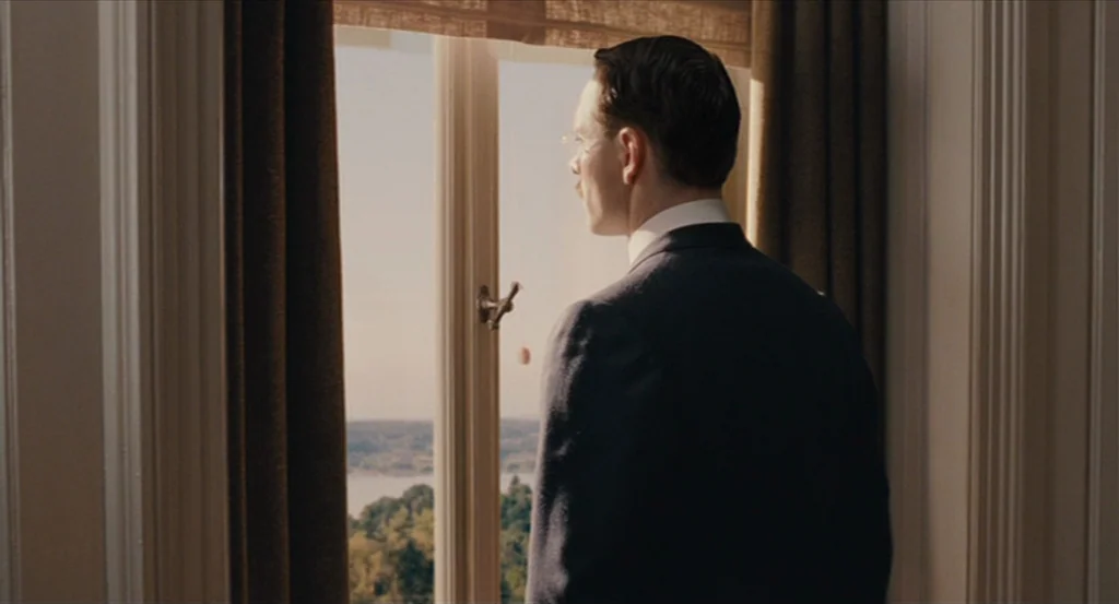 A Dangerous Method movie still: medium — A man stands in a room with light-colored walls and heavy curtains. He gazes through a tall window…