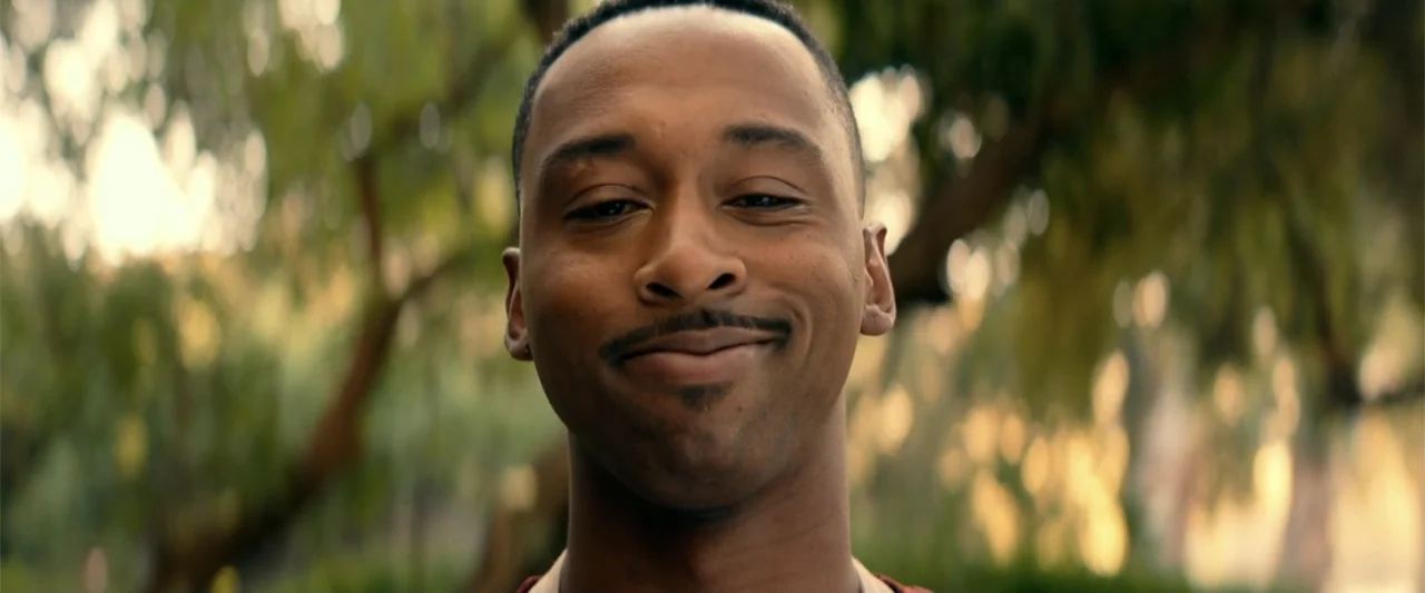 Bad Boys: Ride or Die (2024) movie still: closeup — A man stands outdoors in front of out-of-focus green trees during late afternoon. The man looks…