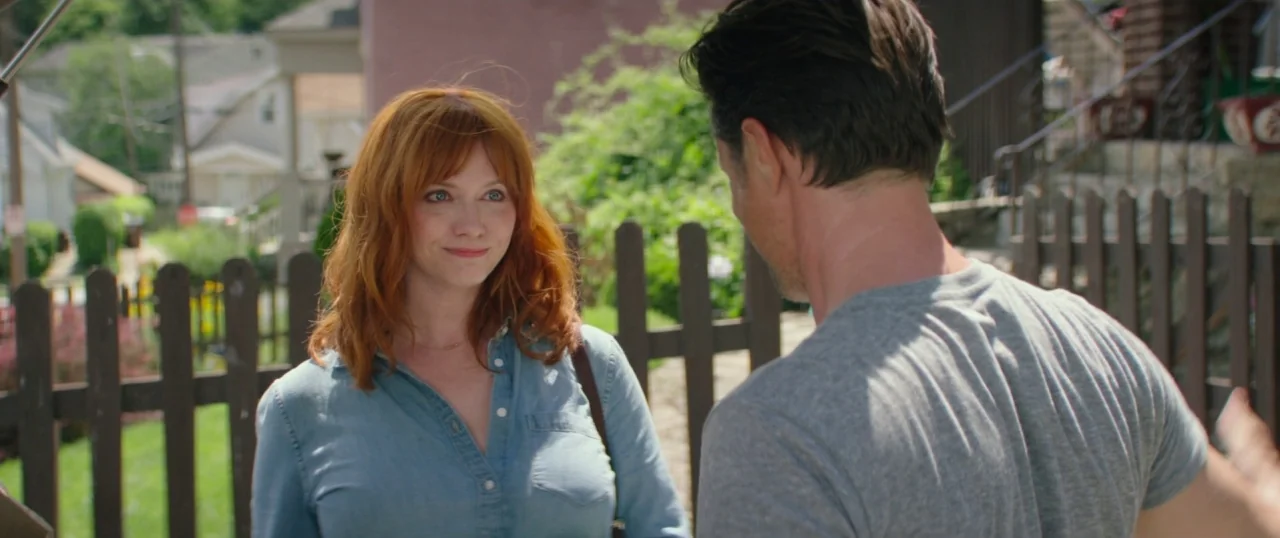 The Strangers: Prey at Night (2018) movie still: medium — A residential front porch with a wooden fence and blurred houses in the background. A…
