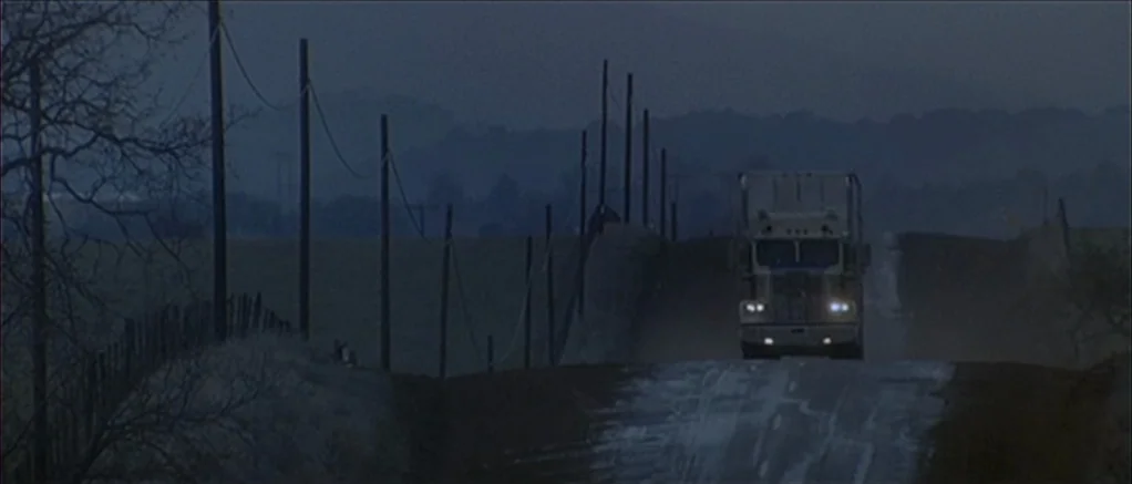 Big Trouble in Little China (1986) movie still: wide — A rural dirt road stretches through open fields lined with wooden telephone poles. A large…