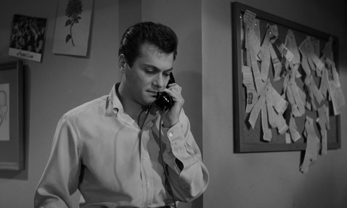 Sweet Smell of Success (1957) movie still: medium — An office wall is decorated with a cork bulletin board and various framed prints. A man with…