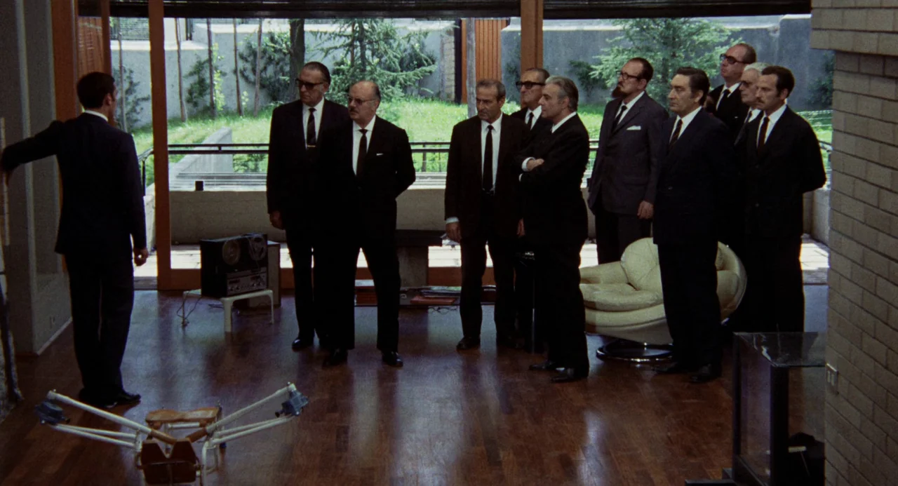 Investigation of a Citizen Above Suspicion (1970) movie still: wide — A modernist interior with floor-to-ceiling glass walls overlooks a green…