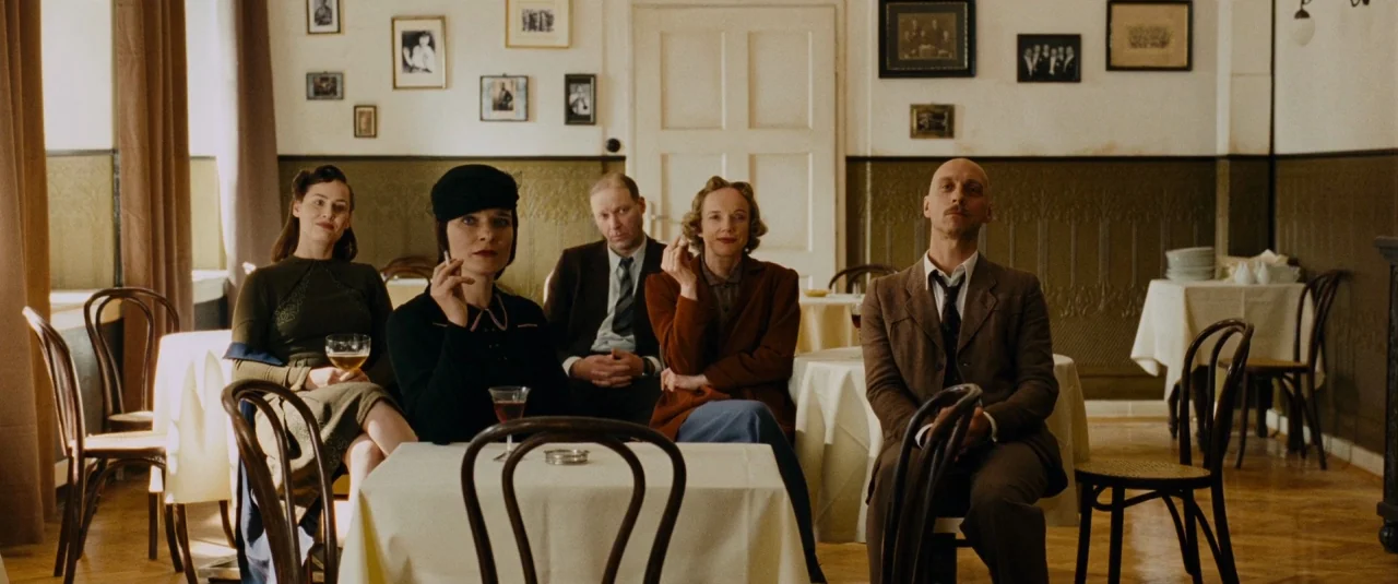 Phoenix (2014) movie still: wide — A 1940s restaurant with pale walls, dark wainscoting, and small framed photographs. Five people sit at two tables…