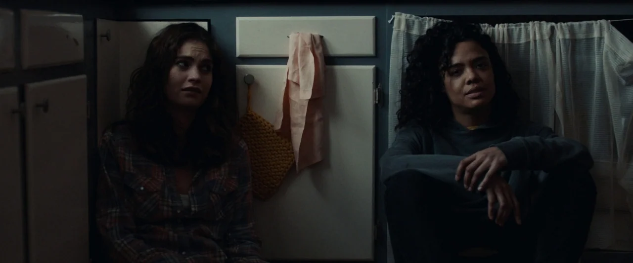 Little Woods (2018) movie still: medium — Two women are sitting on the floor against a plain wall with cupboards. They are positioned side-by-side…