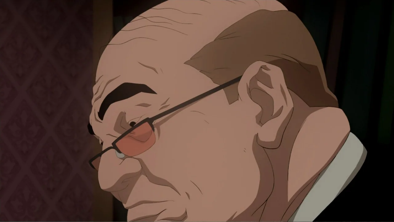 Batman: Year One (2011) movie still: closeup — An interior space features patterned wallpaper in deep red tones. An elderly man with glasses looks…