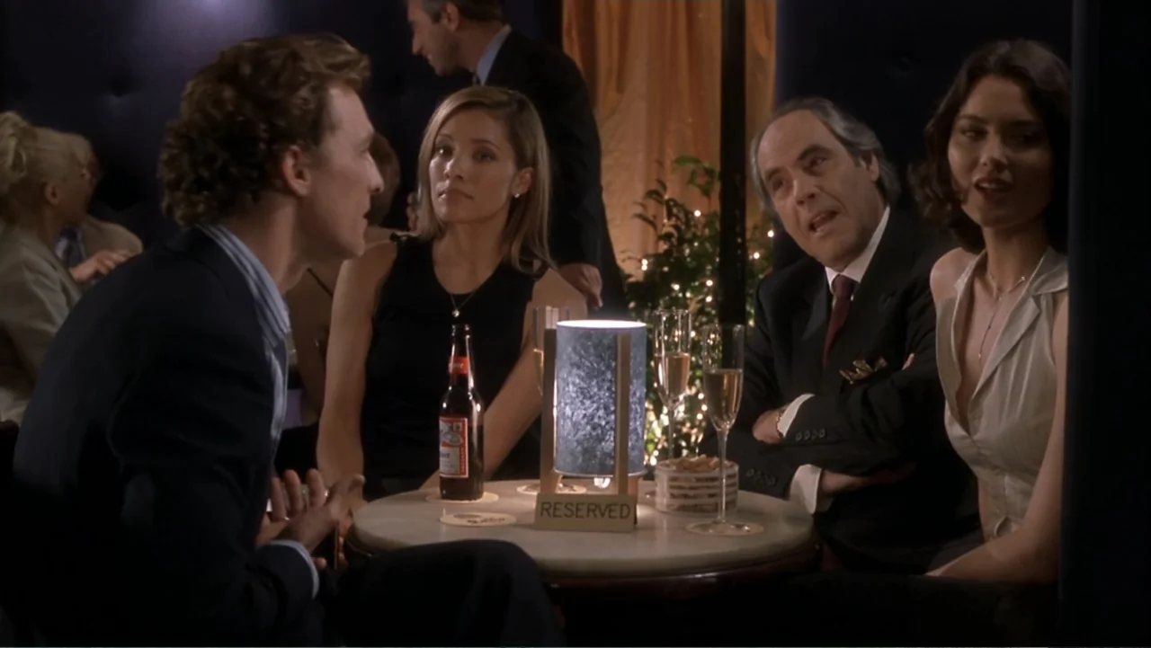 How to Lose a Guy in 10 Days (2003) movie still: medium — A dimly lit lounge setting features people seated at a round table. Four adults engage in…