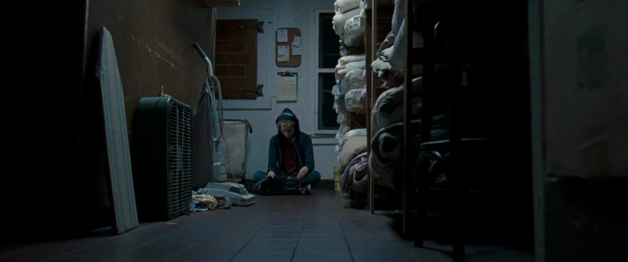 The Innkeepers (2011) movie still: wide — A cramped storage room is filled with shelving units holding stacked white linens and household items. A…