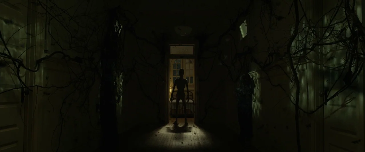 Before I Wake (2016) movie still: wide — A dark, narrow interior hallway is choked with thick, leafless woody vines. A slim, pale humanoid figure…