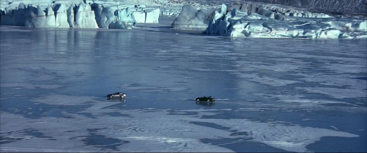 Die Another Day (2002) movie still: wide — A vast, flat expanse of frozen ice stretches between massive, jagged glacial ice formations. Two small…