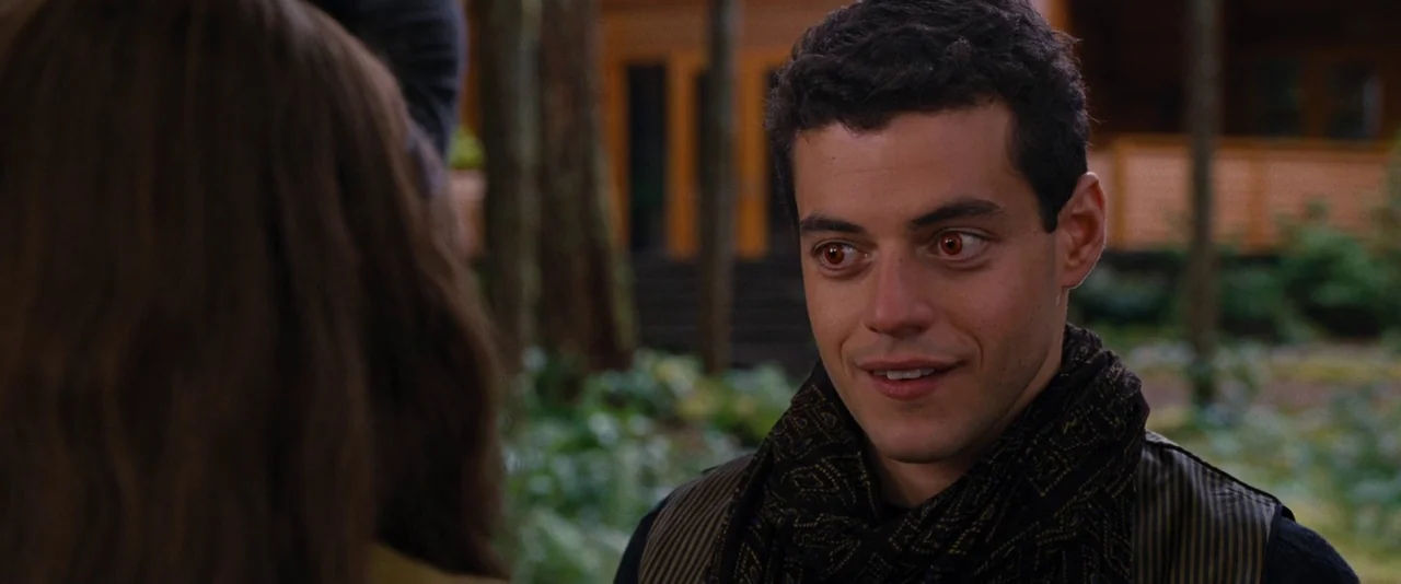 The Twilight Saga: Breaking Dawn – Part 2 (2012) movie still: medium — A man with orange-tinted eyes interacts with another person in a wooded…