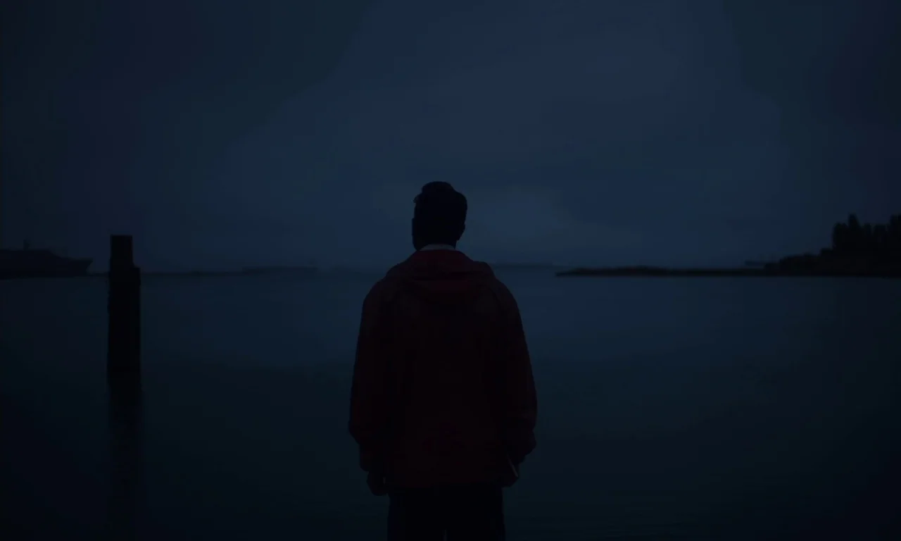 The Last Black Man in San Francisco (2019) movie still: medium — A dark dock area overlooks a vast expanse of water under a dim sky. A man in a…