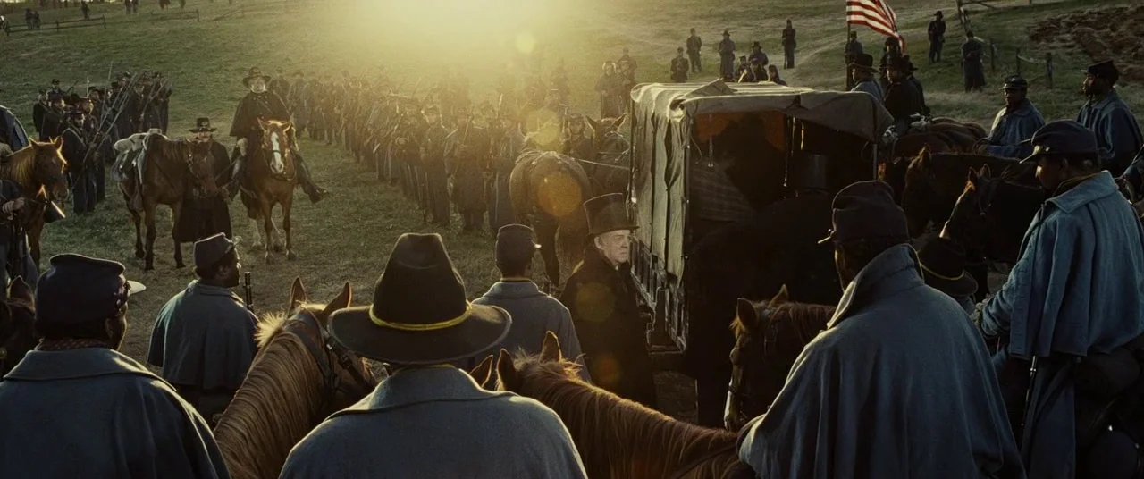 Lincoln (2012) movie still: wide — A wide field holds a large group of American Civil War era soldiers. Many are on horseback, facing a wagon while…
